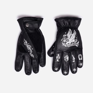May include: Black leather gloves with white graphic designs. One glove features a snake design, while the other has an eagle with the word "FREEDOM" and other symbols. The gloves have a button closure.