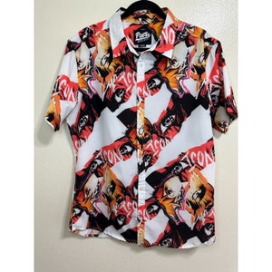 May include: White button-down shirt with a short sleeve and a colorful print of eyes and the word "ICON" repeated. The shirt has a label that says "Pacific" on it.