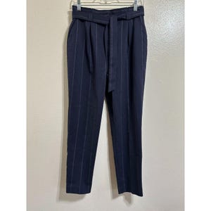May include: Dark blue pinstripe pants with a wide belt. The pants have a high waist and a straight leg.