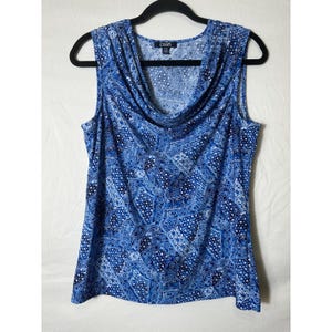 May include: Sleeveless blue top with a cowl neck and a repeating white and blue pattern. The top is hanging on a black hanger. The tag reads "Chaps".