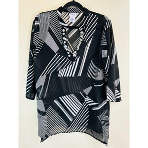 May include: Black and white striped sheer tunic top with a V-neck and button accents. The top has a geometric pattern and a slightly longer back hem.