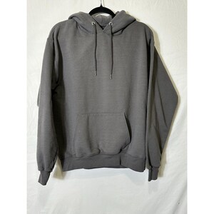 May include: A charcoal gray hoodie with a drawstring hood and a kangaroo pocket. The sweatshirt has ribbed cuffs and a ribbed hem. The hoodie is hanging on a black hanger against a white background.