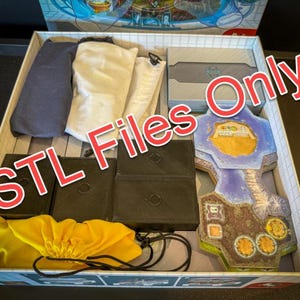 May include: An open box containing a variety of items, including two black boxes, two white bags, a yellow bag, and a multi-coloured game board. The text "STL Files Only" is superimposed on the image.