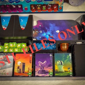 May include: A game box insert with compartments for storing game pieces. The insert has a black and blue color scheme and includes compartments for dice, cards, and other game components. The insert is designed to fit a specific game box.