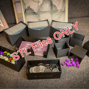 Pode incluir: Um conjunto de caixas de armazenamento de plástico preto para organizar as peças do jogo. As caixas são projetadas para conter componentes de vários tamanhos, incluindo fichas pequenas, cartas e dados. As caixas são etiquetadas com o texto "STL Files Only".