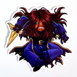 Op de afbeelding: Een sticker met een stripfiguur met rood haar, een oranje gezicht en blauwe kleding. Het personage houdt een gouden dolk vast. De sticker heeft een witte rand en de handtekening van de kunstenaar, "BREPA!", is zichtbaar.