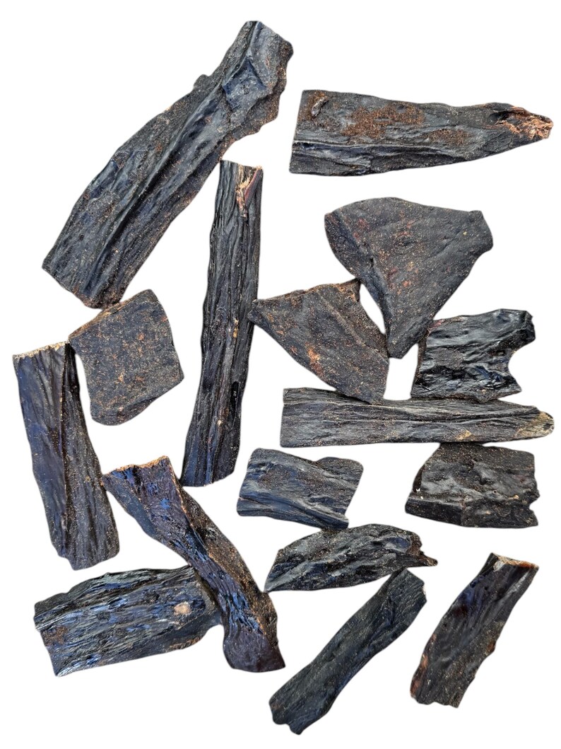 May include: A collection of 13 dark brown, dried, and irregularly shaped pieces of beef jerky.