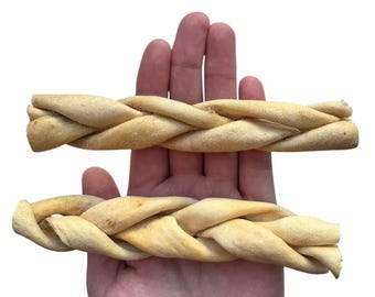 May include: Two braided dog chews made of natural, light brown, dried bully sticks. The chews are different sizes and are held in a person's hand.