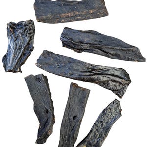 May include: Seven dark brown dried beef jerky strips, some are long and thin, others are short and thick, all are irregularly shaped.