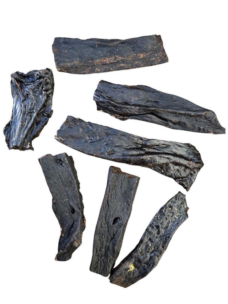 May include: Seven dark brown dried beef jerky strips, some are long and thin, others are short and thick, all are irregularly shaped.