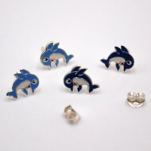 May include: A pair of silver dolphin stud earrings. The dolphins are blue and white with red accents. The earrings are on a white background.