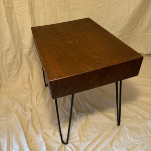 May include: A dark brown wooden table with a rectangular top and black hairpin legs. The table is sitting on a white fabric surface.