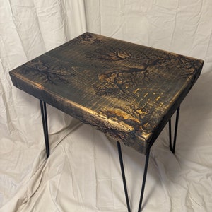 May include: A black wooden side table with a unique wood grain pattern and black hairpin legs.