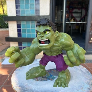 Könnte beinhalten: Eine grüne Hulk-Figur mit einem violetten Lendenschurz, die mit geballten Fäusten und einem wütenden Gesichtsausdruck steht. Die Figur ist aus Kunststoff und etwa 25 cm groß.