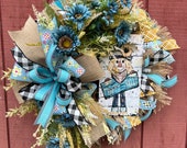 Fall wreath with a scarecrow and blue sunflowers and golden accents, scarecrow sign and hay like texture perfect for your front door