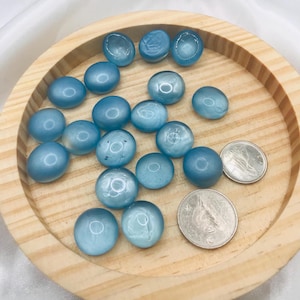 Peut inclure: Un bol en bois rempli de galets de verre bleu clair. Le bol est sur une surface blanche.