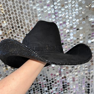May include: A black cowboy hat with a wide brim and a band of rhinestones around the crown.