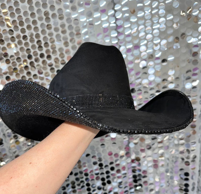 May include: A black cowboy hat with a wide brim and a band of rhinestones around the crown.
