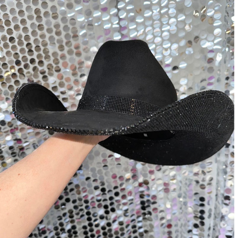 May include: A black cowboy hat with a black rhinestone band and trim.
