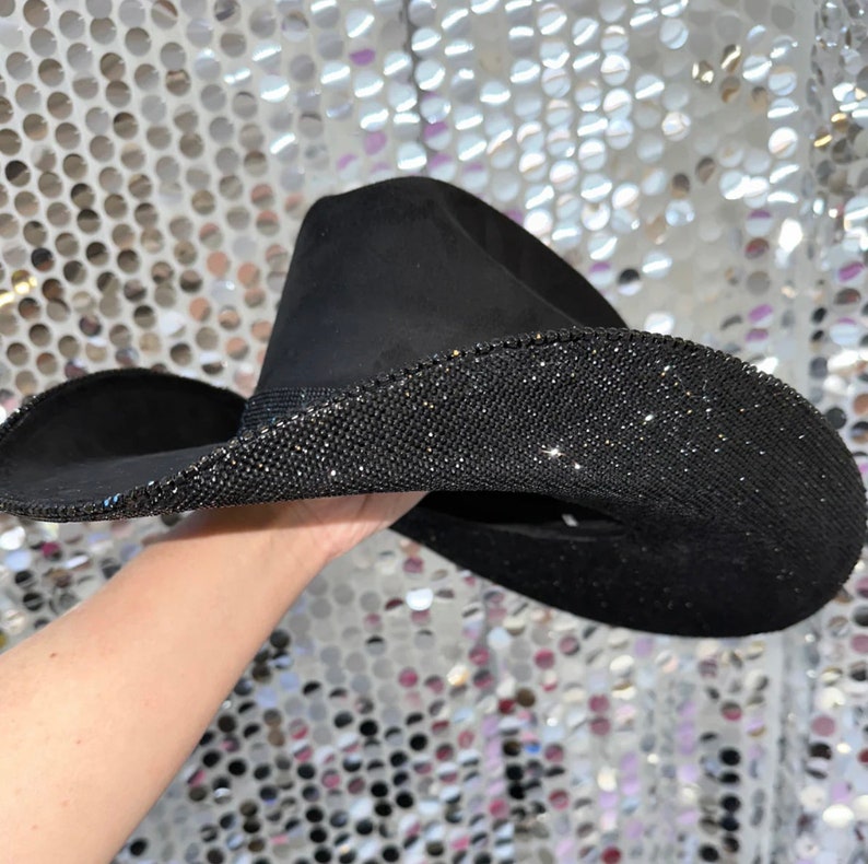 May include: A black cowboy hat with a wide brim, decorated with a band of sparkling rhinestones.