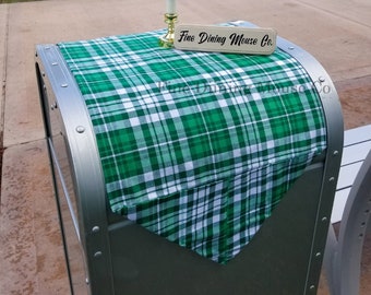 May include: A green and white checkered tablecloth is draped over a silver metal trash can. A small wooden sign with the text "Fine Dining Mouse Co." is placed on top of the tablecloth. A small candle is in front of the sign.