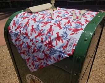 May include: A white tablecloth with a red lobster and blue coral pattern. The tablecloth is on top of a green mailbox. The text "Time Dining Mouse Co." is visible on the tablecloth.