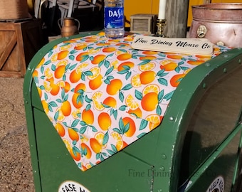 May include: A green metal trash can with a white and orange fabric liner with a citrus pattern. The can has a sign that says "Fine Dining Mouse Co." and a bottle of water on top of the liner. The can also has a sticker that says "Please Help Keep Our...