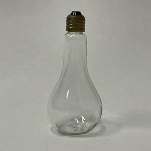 May include: A clear glass bottle shaped like a light bulb with a brown and black screw-on lid.