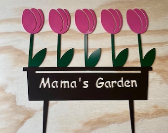 May include: Metal garden stake with five pink tulips in a black planter. The planter has the text "Mama's Garden" written on it.