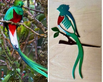 May include: A vibrant image showcases a resplendent quetzal bird perched on a branch, displaying its iridescent green, red, and white plumage. The bird's long, flowing tail feathers are a striking feature. Next to it is a metal cutout of the same bird.