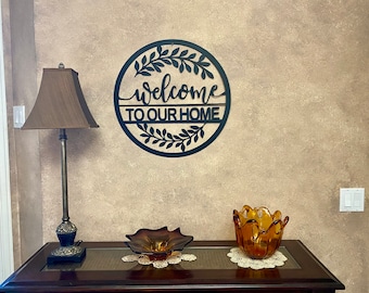 May include: Black metal wall decor with a wreath and the words "Welcome to our home".