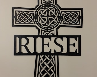 May include: Black metal Celtic cross with intricate knotwork design and the name "RIESE" inscribed below.