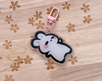 May include: A white bunny keychain with pink accents and a black outline. The keychain has a pink metal clasp.