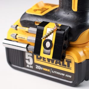 May include: A yellow and black DeWalt 20V MAX Lithium Ion battery pack with a black accessory holder. The holder contains several drill bits and a screw. The battery pack is labeled with "5 AH".
