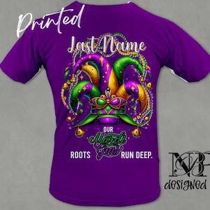 May include: Purple t-shirt with a Mardi Gras jester hat design. The text "Last Name" is above the hat and "Our Mardi Gras Roots Run Deep." is below the hat. The text "MP Designed It" is in the bottom right corner.