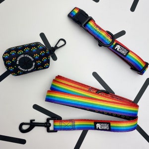 May include: A rainbow dog leash and collar set with black hardware. The leash and collar are both made of durable nylon and feature a rainbow pattern with the text "The House of Dawg" printed on them.