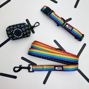 May include: A rainbow dog leash and collar set with black paw prints and the text "The House of Dawg".