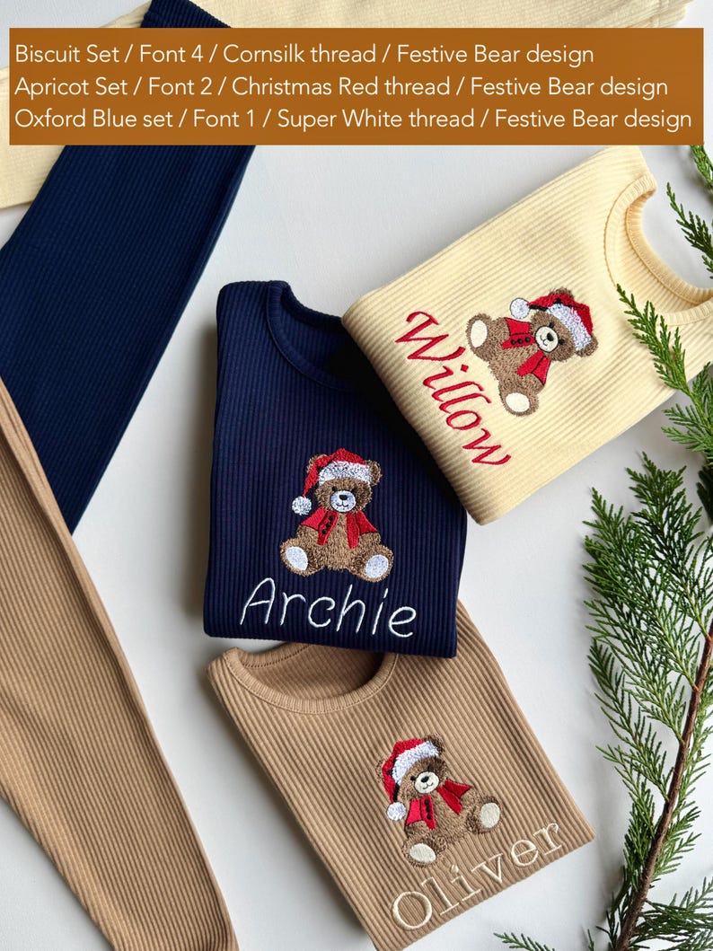 May include: Ribbed knit shirts in navy blue, tan, and cream colors, each embroidered with a festive bear design wearing a Santa hat and scarf. The names "Archie", "Willow", and "Oliver" are embroidered below the bear. The image also shows matching pants.