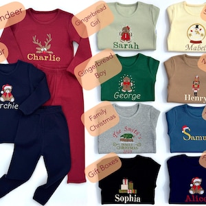May include: Collection of children's Christmas pajamas in various colors, including red, navy, green, and beige. Each set features embroidered holiday-themed designs like reindeer, gingerbread people, snow globes, and bears. Names are embroidered on the shirts.
