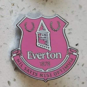 Puede incluir: Un pin de esmalte rosa y plateado con el escudo del Everton Football Club. El escudo incluye una torre, dos coronas y el texto "Everton 1878 Nil Satis Nisi Optimum".