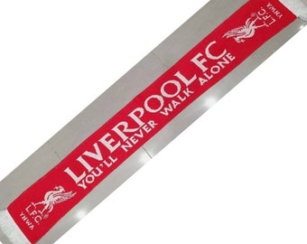 Può includere: Sciarpa rossa e bianca con le parole "Liverpool FC You'll Never Walk Alone" e il logo del Liverpool FC. La sciarpa ha frange bianche su entrambe le estremità.