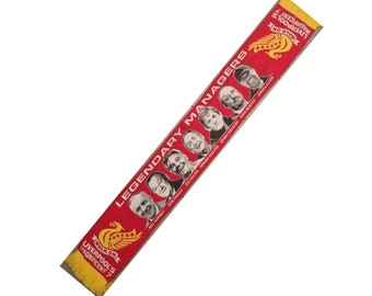 Op de afbeelding: Een rode en gele sjaal met de tekst "Walk On Liverpool's Magnificent 7" en "Legendary Managers" met foto's van managers waaronder Bill Shankly, Bob Paisley, Joe Fagan, Gerard Houllier, Kenny Dalglish, Rafa Benitez en Jürgen Klopp.