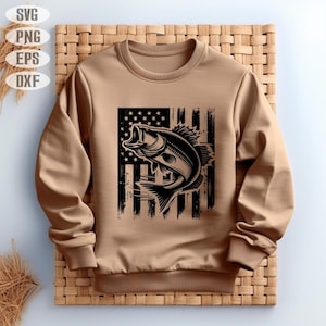 K&ouml;nnte beinhalten: Ein braunes Sweatshirt mit einer schwarzen und wei&szlig;en Grafik eines Fisches, der aus einer notleidenden amerikanischen Flagge springt.