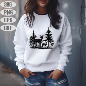 May include: A white sweatshirt with a black silhouette of a mother deer and fawn standing in a forest. The deer are surrounded by trees and foliage.