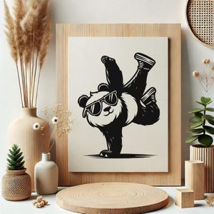May include: A black and white illustration of a panda wearing sunglasses, performing a handstand. The panda is set against a cream background, framed in light wood. The image is surrounded by decorative vases, plants, and wooden accents.