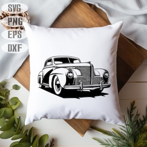 May include: White square pillow featuring a black and white illustration of a classic vintage car. The car design is a detailed line drawing, showcasing the vehicle's front and side profile. The pillow is placed on a wooden surface.