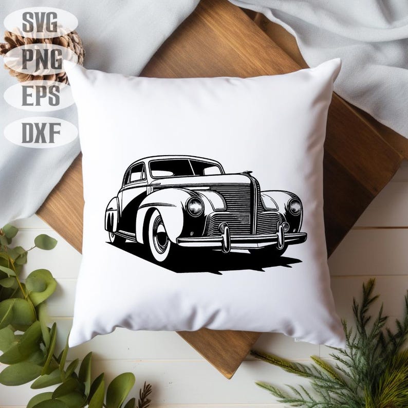 May include: White square pillow featuring a black and white illustration of a classic vintage car. The car design is a detailed line drawing, showcasing the vehicle's front and side profile. The pillow is placed on a wooden surface.