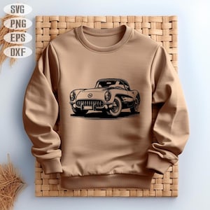 May include: A tan sweatshirt featuring a black and white illustration of a classic car. The car is a vintage model with detailed headlights, grille, and wheels. The sweatshirt has a crew neck and long sleeves, and is displayed on a woven background.