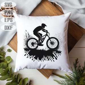 Op de afbeelding: Een wit kussen met een zwart-wit silhouet van een persoon die mountainbike rijdt. De fiets is omringd door zwarte verfspatten.