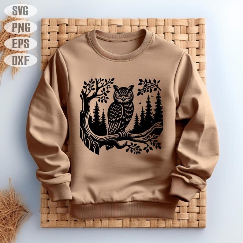 May include: A brown sweatshirt with a black silhouette of an owl perched on a branch in a forest setting.